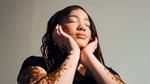 Vrouw met vitiligo en gevlochten haar laat haar gezicht met gesloten ogen in haar handen rusten.
