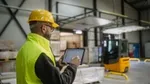 Twee mannen in witte laboratoriumjassen en veiligheidshelmen in een industriële faciliteit.