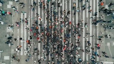 Luchtfoto van een groot aantal mensen die een weg oversteken.
