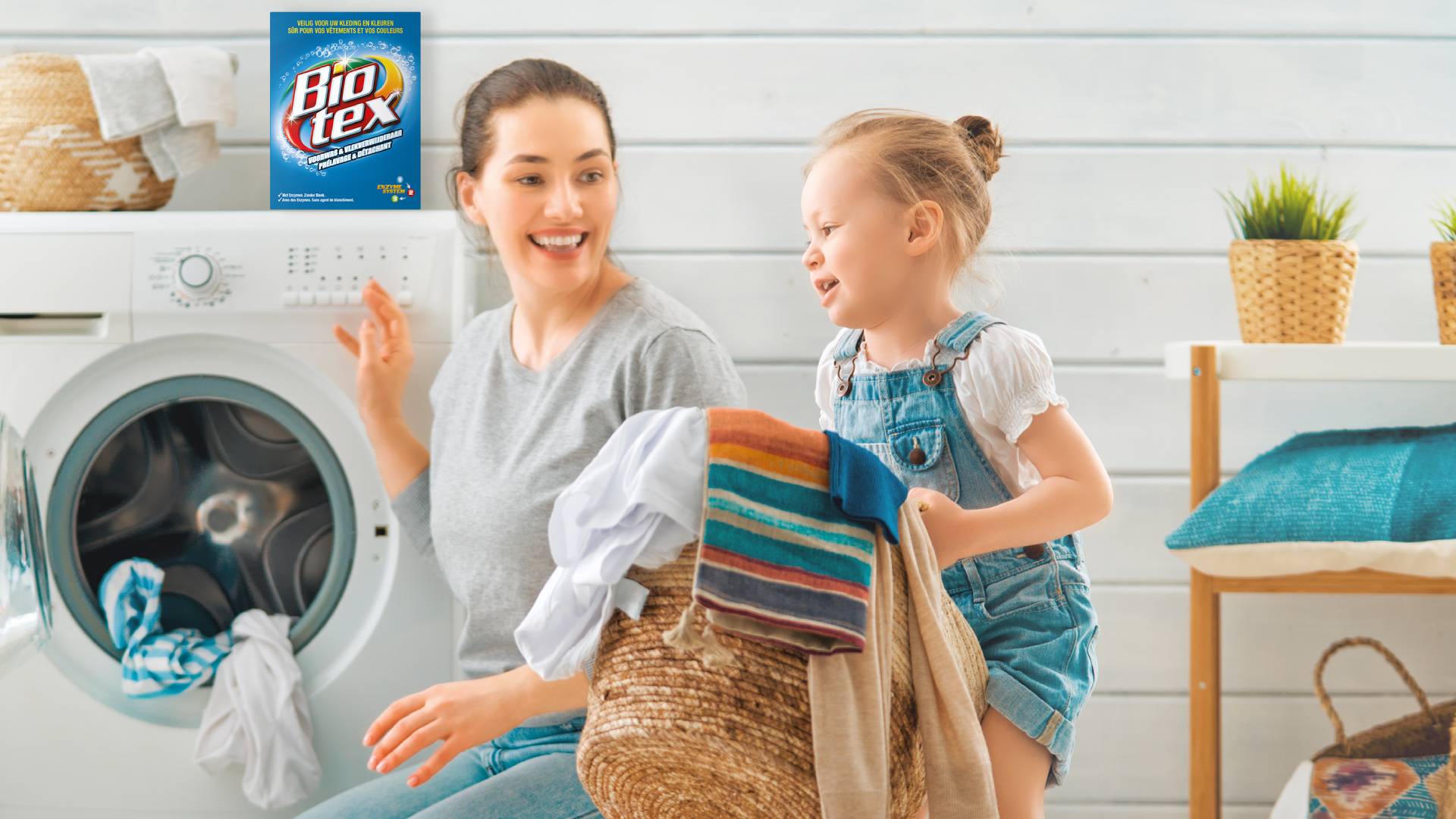 Op de banner is een moeder te zien die samen met haar dochtertje kleding uit de wasmachine haalt