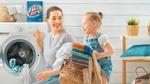 Op de banner is een moeder te zien die samen met haar dochtertje kleding uit de wasmachine haalt